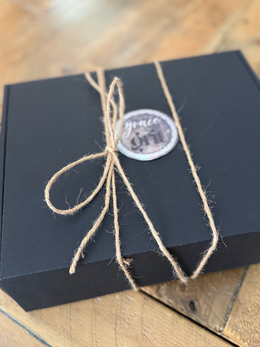 Black box tied with twine and a round label on a wooden surface