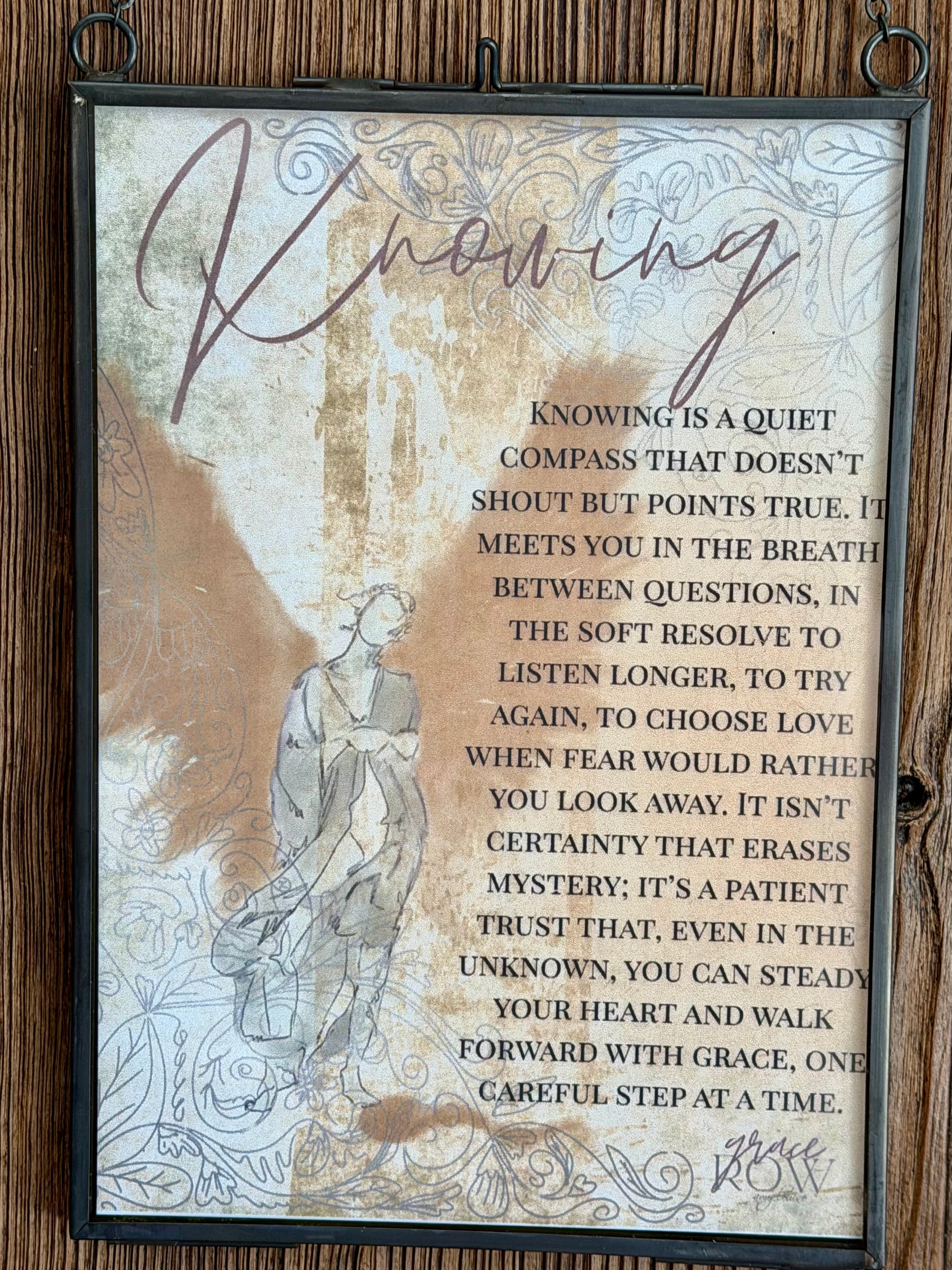 Framed text artwork with a quote on a wooden background
