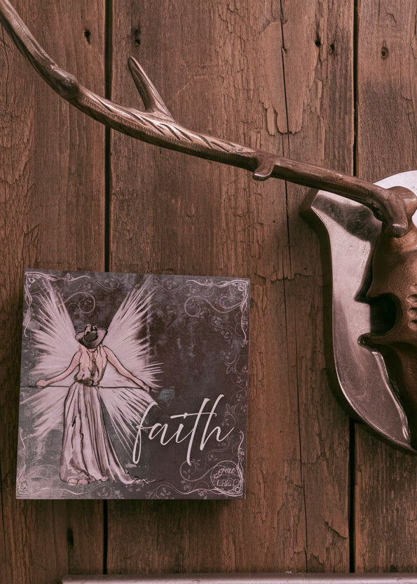 Decorative deer head mount on a wooden wall with a 'faith' sign below.