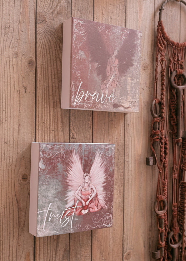 Decorative wall art with angel illustrations and a dreamcatcher on a white wall.